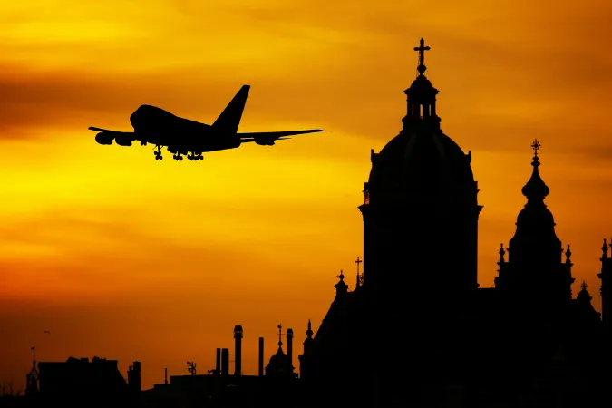 Avião voando ao pôr do sol sobre a cidade. Acompanhe seu voo em tempo real.
