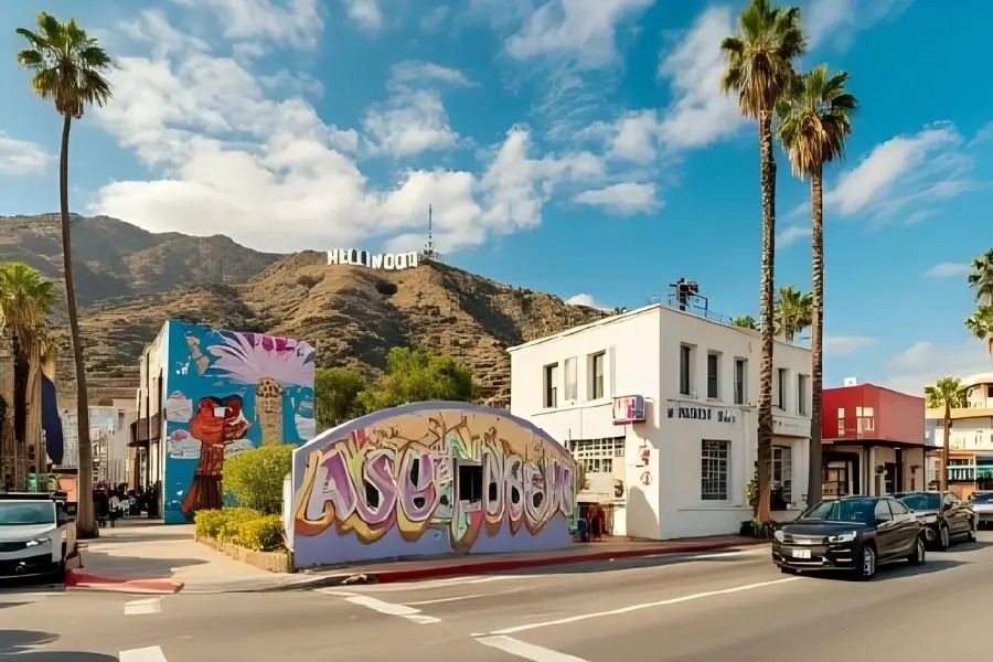 Paisagem urbana de Los Angeles com o letreiro de Hollywood ao fundo. Arte de rua vibrante e palmeiras. Turismo em LA.