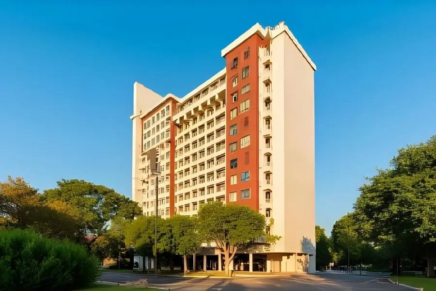 Fachada moderna de hotel de luxo. Arquitetura alta, janelas, varandas e árvores. Hospedagem confortável.
