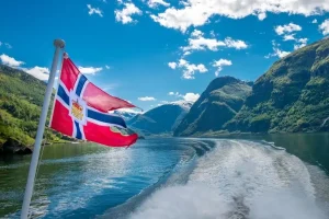 Bandeira da Noruega tremulando em cruzeiro pelos fiordes noruegueses. Paisagens e belezas naturais.
