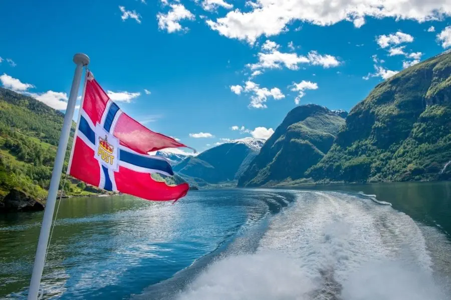 Bandeira da Noruega tremulando em cruzeiro pelos fiordes noruegueses. Paisagens e belezas naturais.