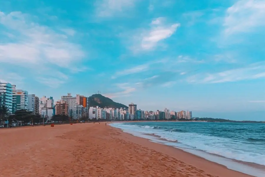 Praia do Morro, Guarapari. Orla com prédios, mar azul e céu com nuvens. Litoral capixaba.