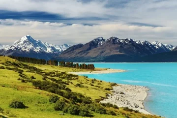 Paisagem épica da Nova Zelândia: lago azul turquesa, montanhas nevadas e colinas verdejantes. Aventura e cultura.