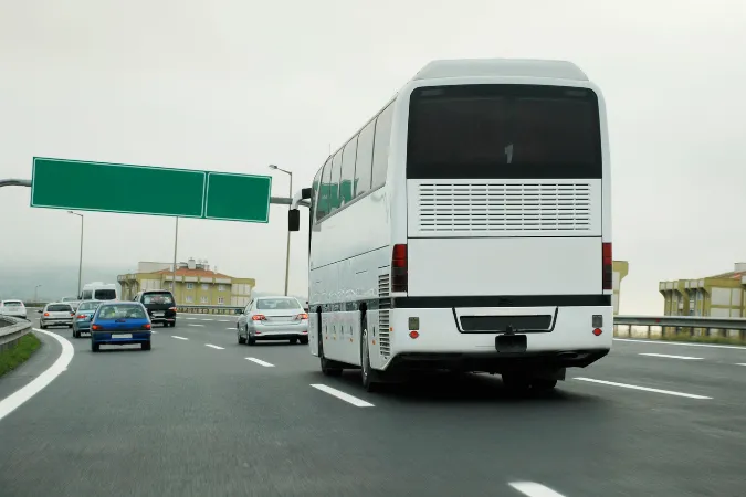 Ônibus executivo branco em rodovia. Ideal para viagens longas e confortáveis. Transporte rodoviário de passageiros.